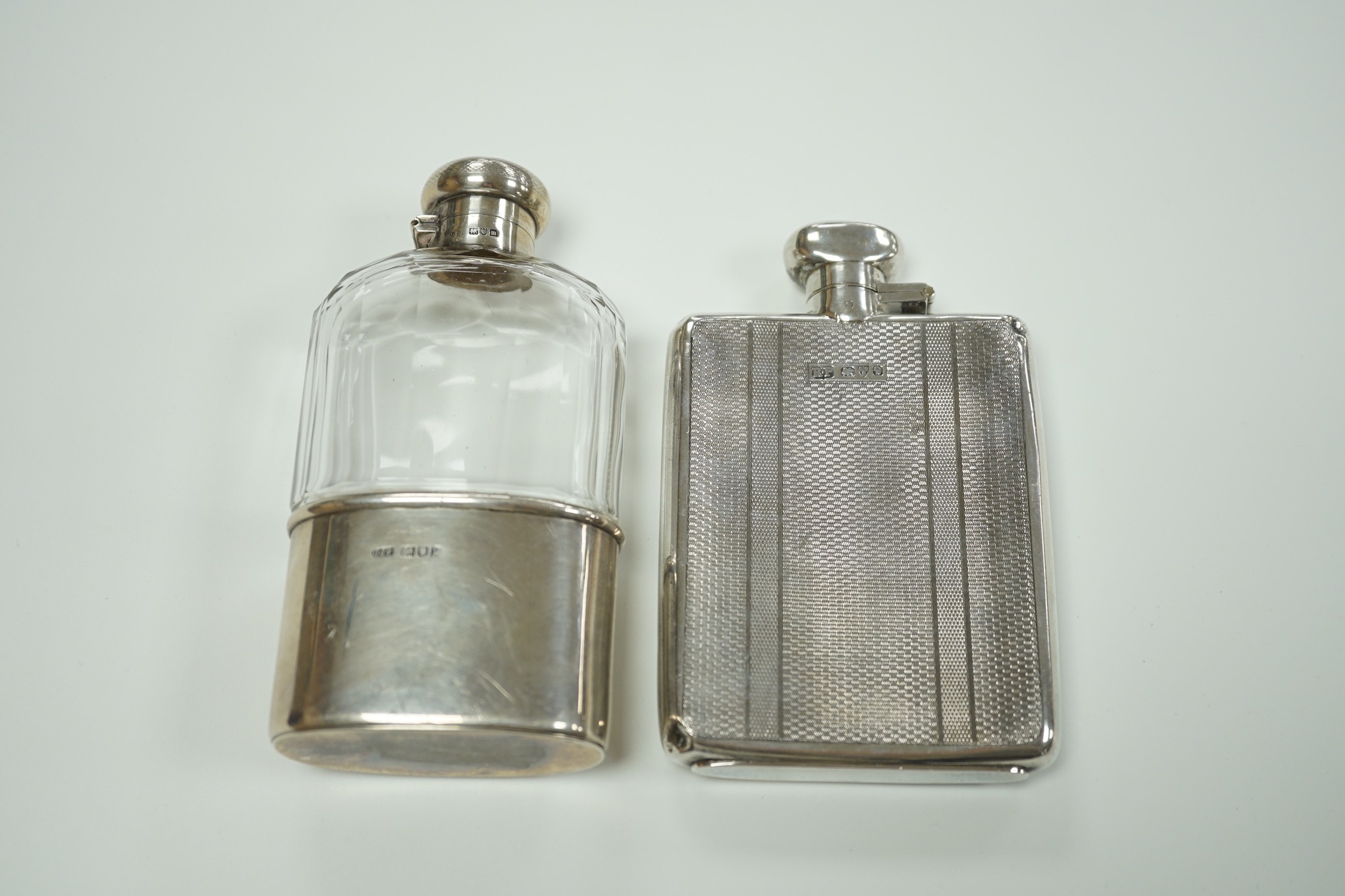 A George V engine turned silver hip flask, by Robert Pringle & Sons, Chester, 1929, 12.8cm and an earlier silver mounted glass hip flask, London, 1910.